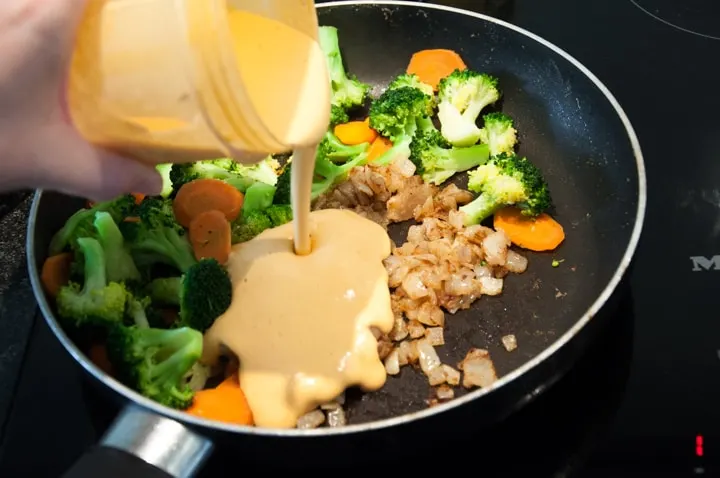 adding cashew sauce to veggies