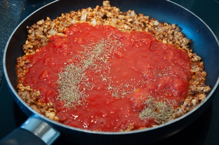 adding diced tomato to tempeh bolognese sauce