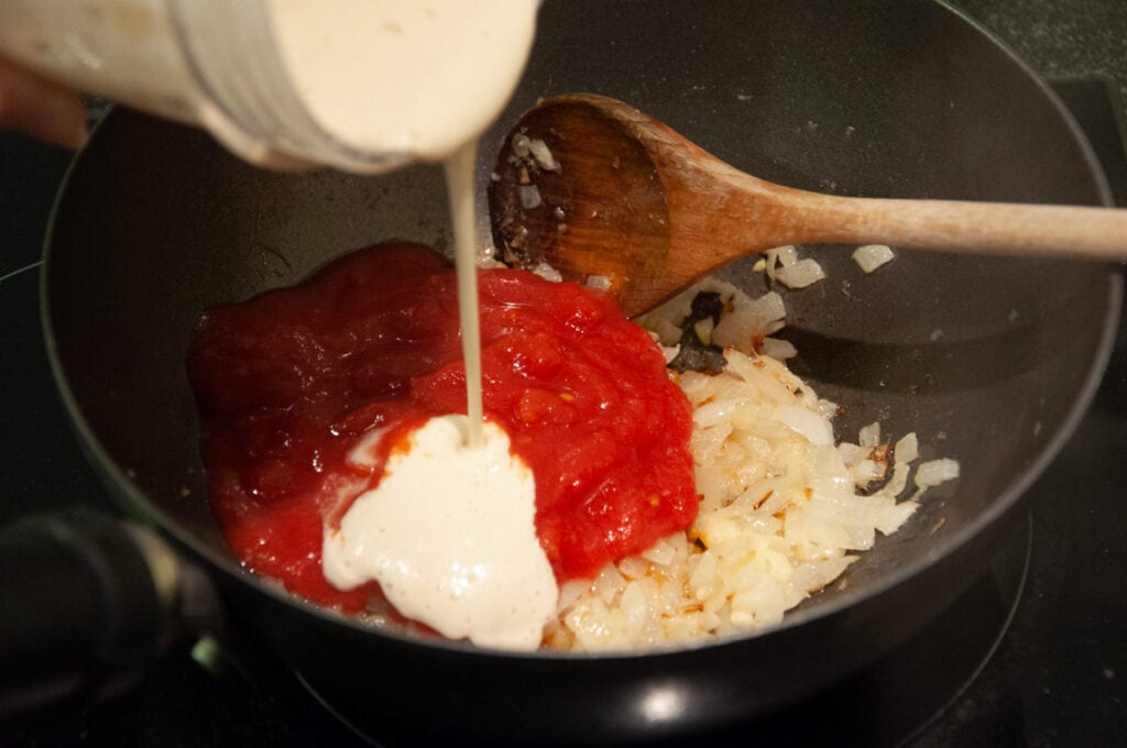 onions, tomato sauce and cashew sauce in pan