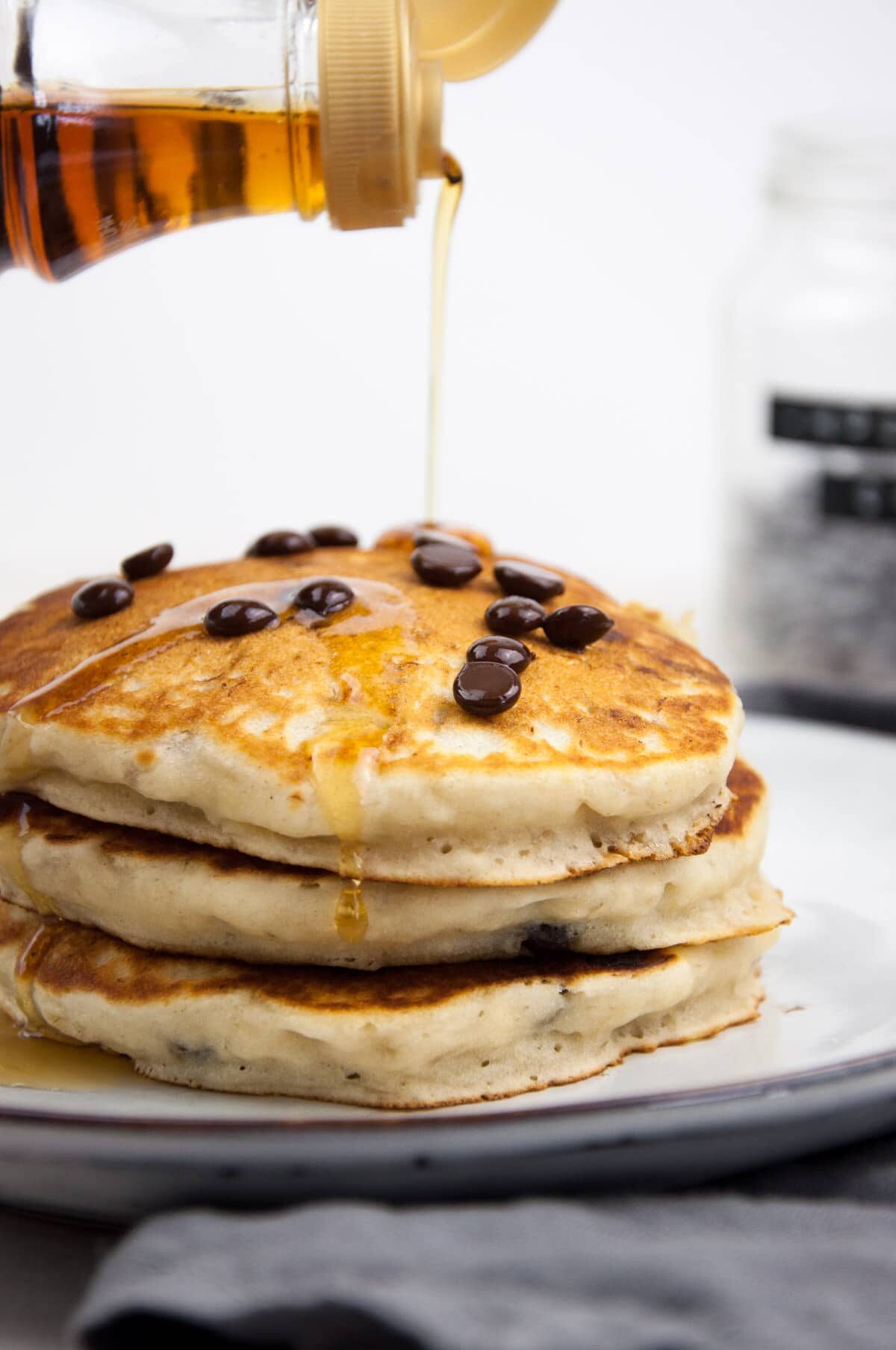 Vegan Chocolate Chip Pancakes drizzled with maple syrup