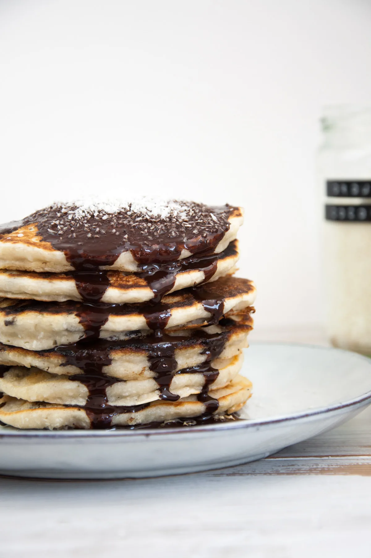 Vegan Coconut Pancakes topped with chocolate sauce and coconut flakes