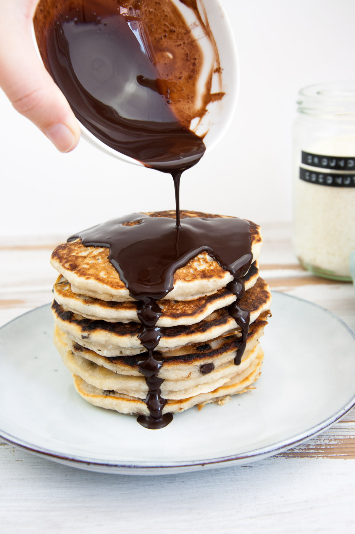 pouring chocolate sauce over coconut pancakes