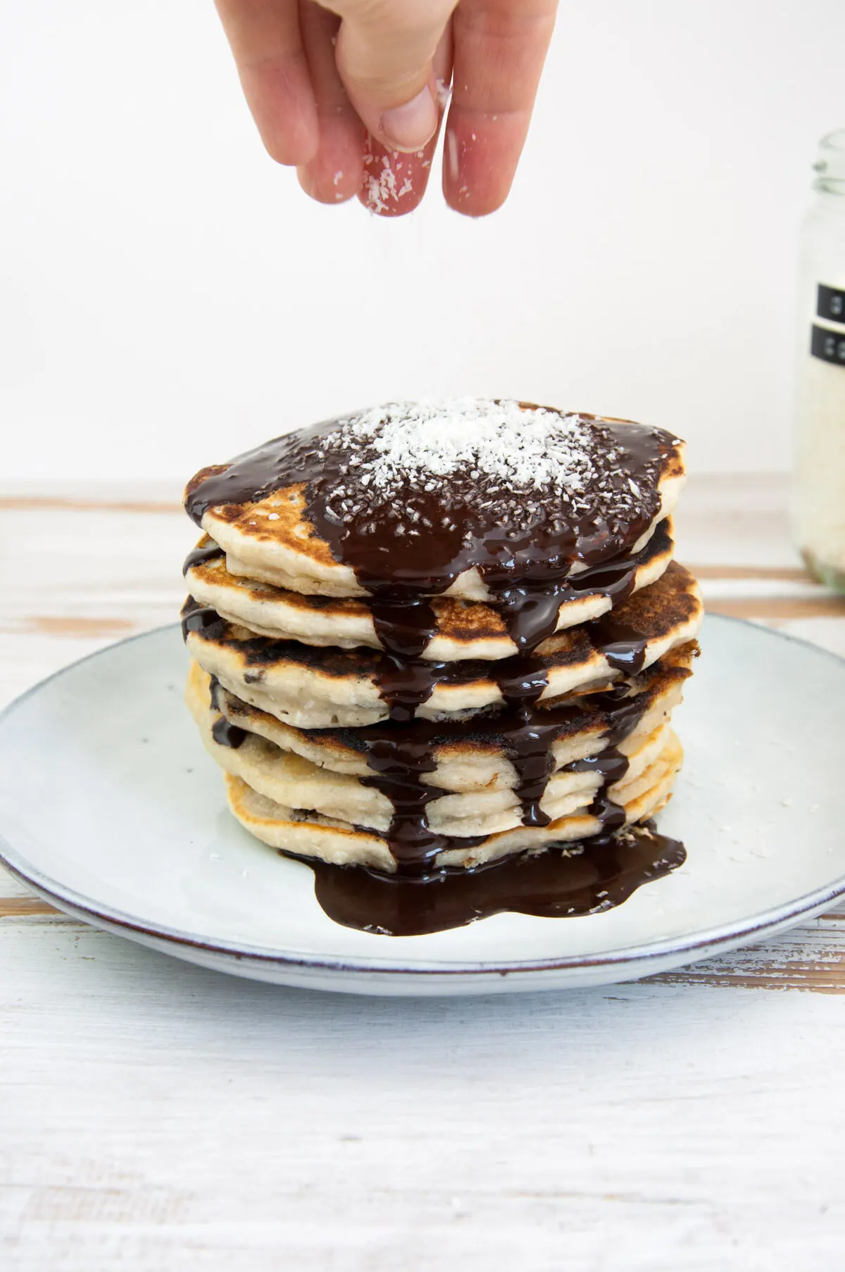 Vegan Coconut Pancakes topped with chocolate sauce and coconut flakes