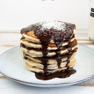 Vegan Coconut Pancakes topped with chocolate sauce and coconut flakes