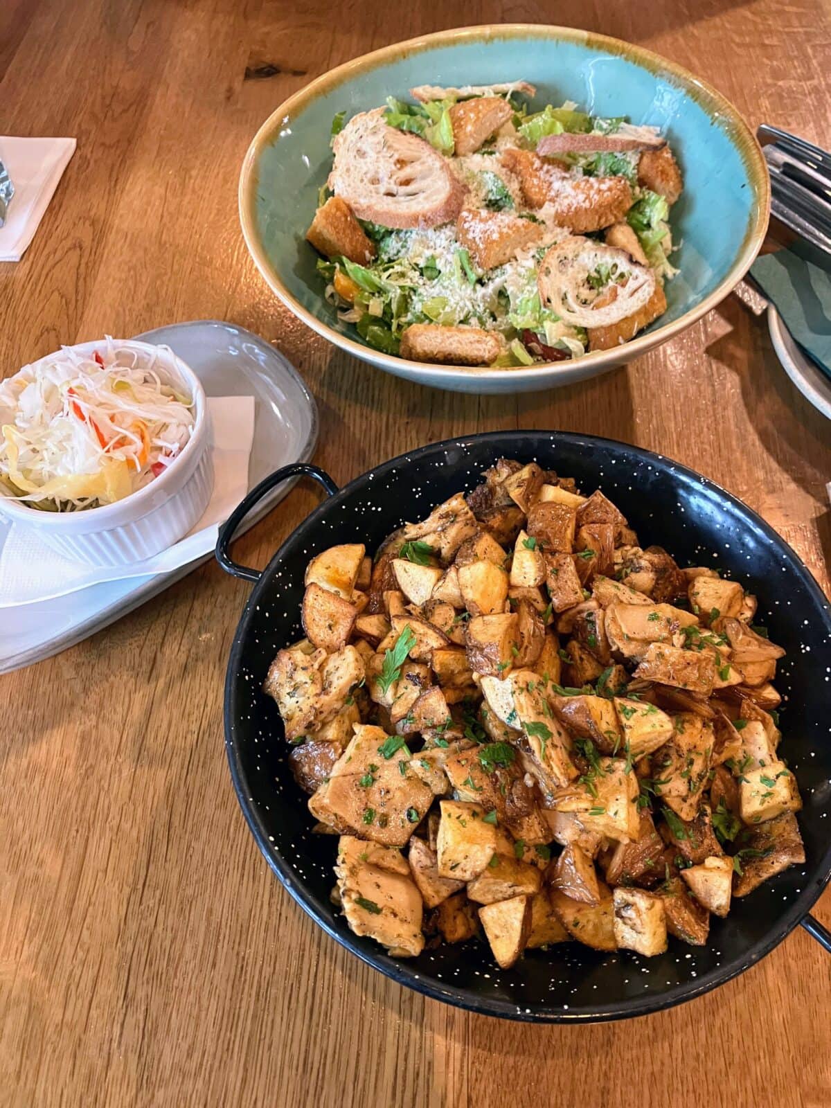 Vegan Caesar salad and tofu stir-fry on wooden table.
